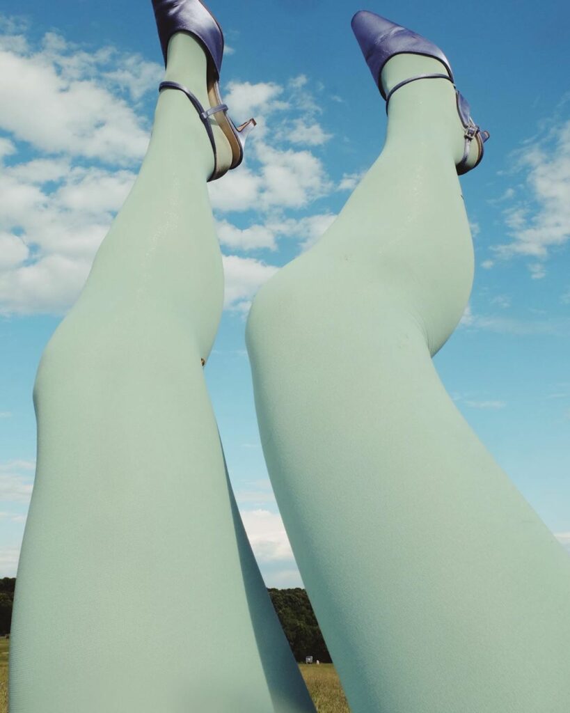 les jambes d'une femme en bas vert d'eau, les pieds tendus vers le ciel