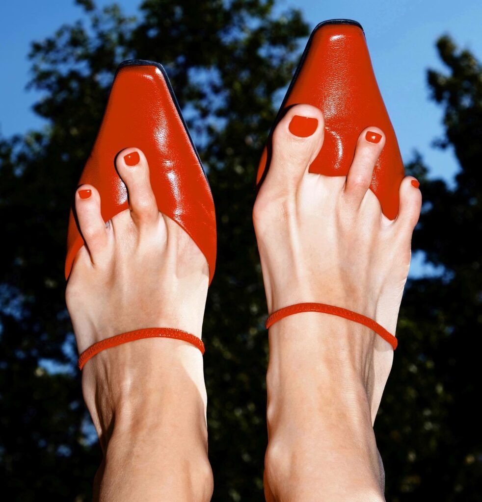 un doigt de pied sur deux dans les escarpins rouges dressés face au ciel