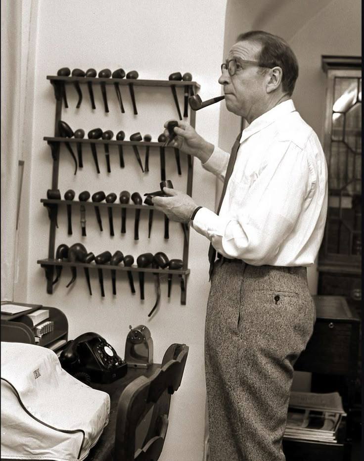 Georges Simenon devant son râtelier de pipes