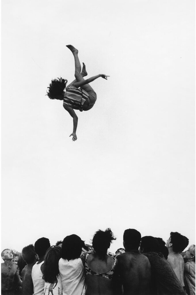 une femme en suspension au dessus de la foule. on ignore si elle monte au ciel ou si elle en descend