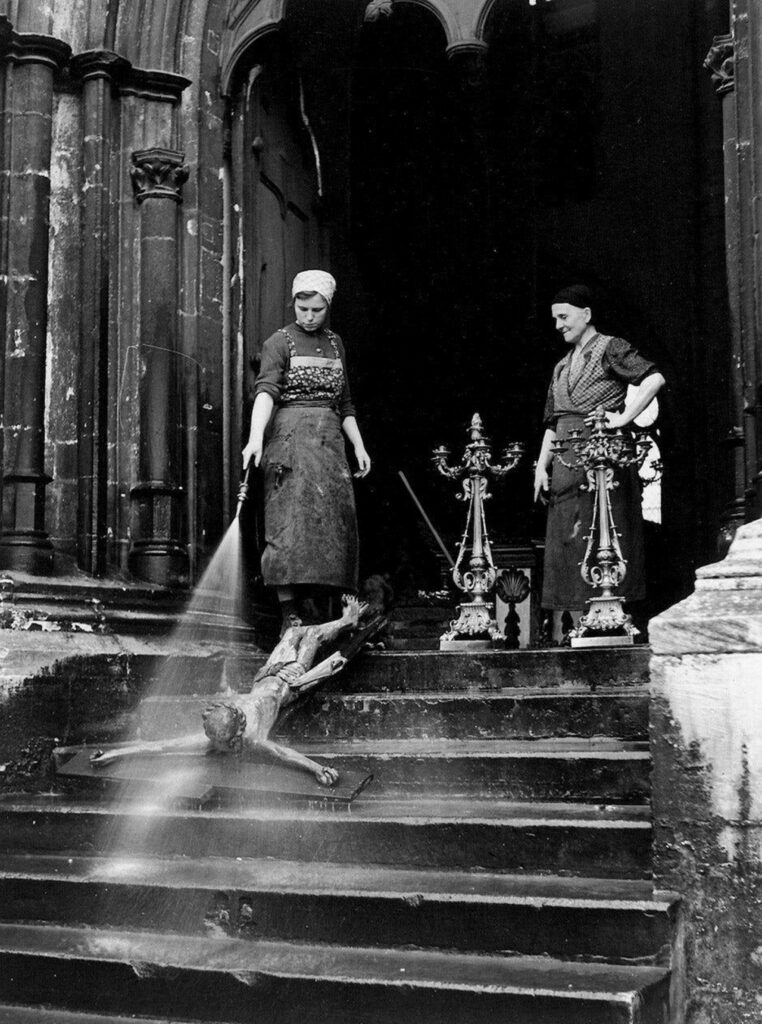 Jésus en croix couché sur le dos sur les marches du temple, passé au jet par deux femmes de ménage chrétiennes