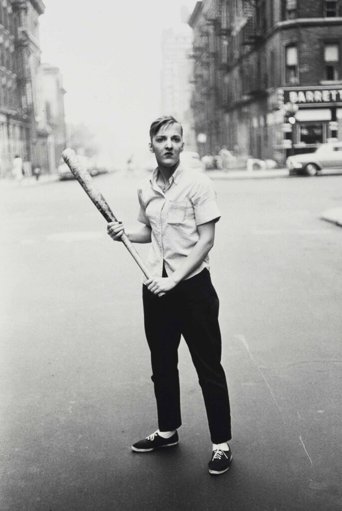un jeune homme au milieu de la rue avec une batte de baseball