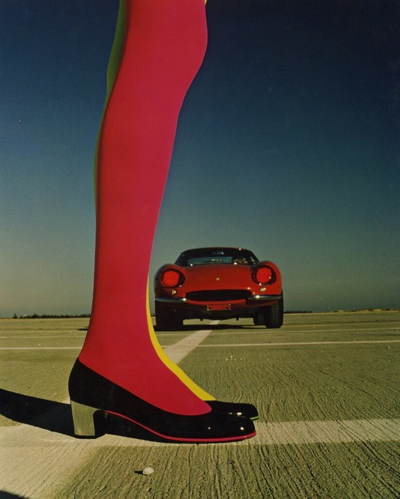 sur sol damier, jambe de femme au bas rouge et voiture de sport assortie