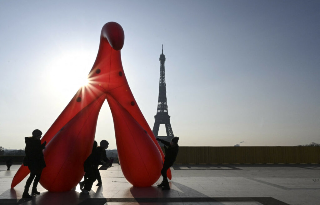 un clitoris gonflable rouge érigé dans le soleil levant devant la tour Eiffel et aussi grand qu'elle