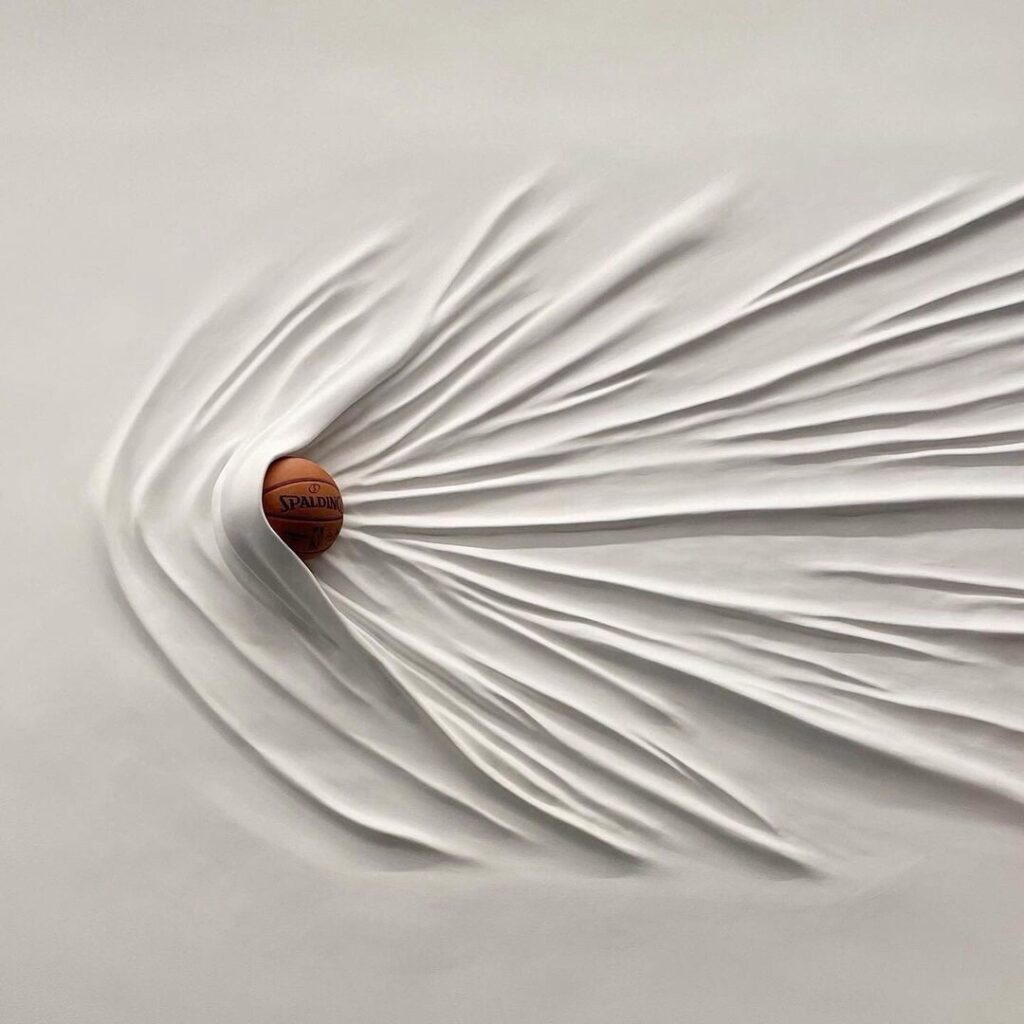 les lignes de force laissées par un ballon de basket dans un tissu blanc où il s'est immobilisé
