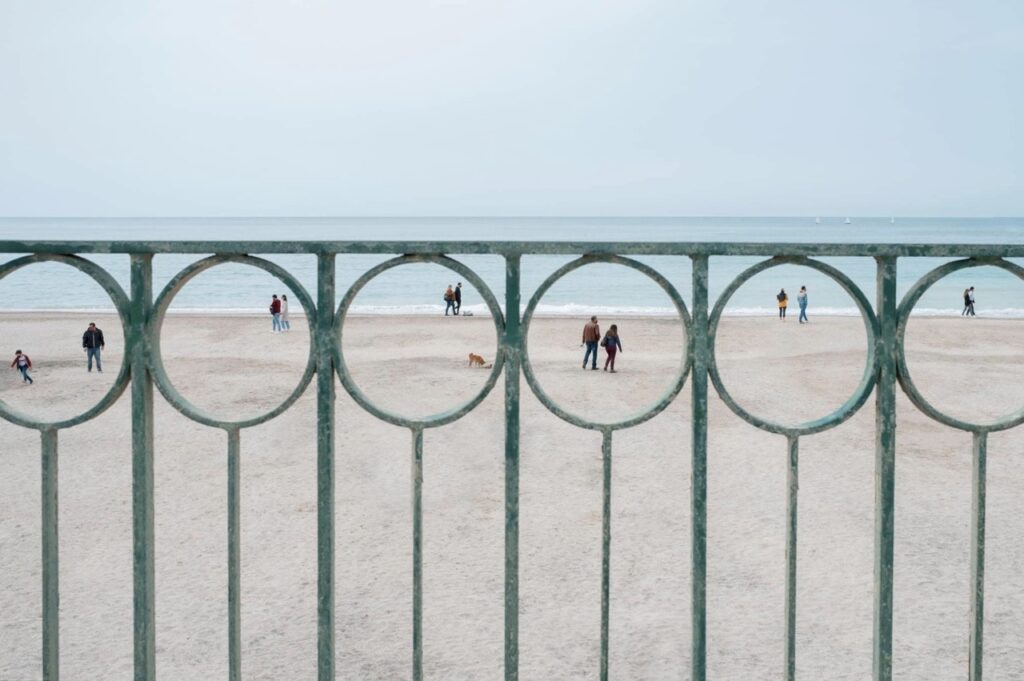 des gens sur la plage, chacun dans un espace circulaire délimité par le motif de la balustrade du remblai 
