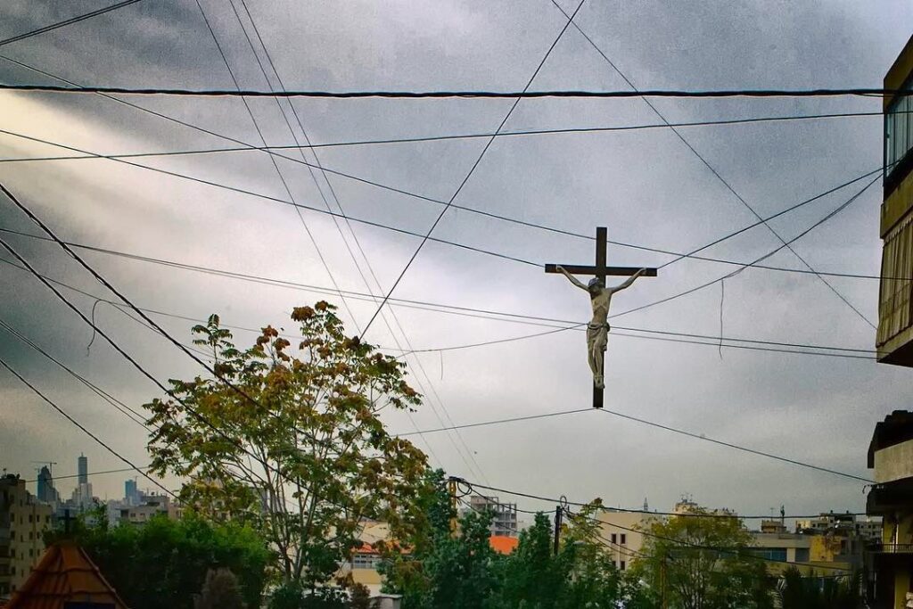 Jésus en croix dans les câbles électriques zébrant le ciel de la ville