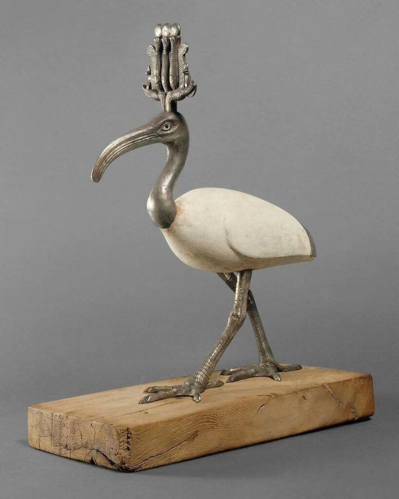 Thot, incarnation de la sagesse et de l'art de l'écriture, était le protecteur des scribes. L'ibis et le babouin étaient les animaux sacrés du dieu Thot. Le corps de cette statuette est en bois recouvert de stuc raffiné. La tête, coiffée de la couronne atef, le cou, les plumes de la queue et les pattes sont en argent. Les yeux sont en stuc et en verre noir.