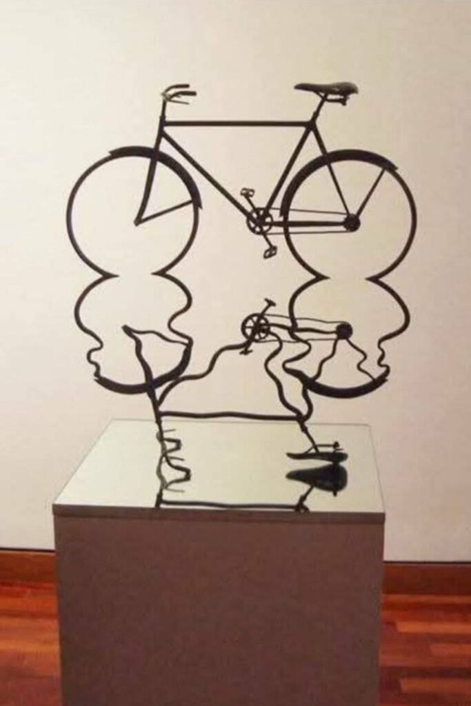 sculpture d'un vélo au reflet déformé comme par la surface d'un liquide