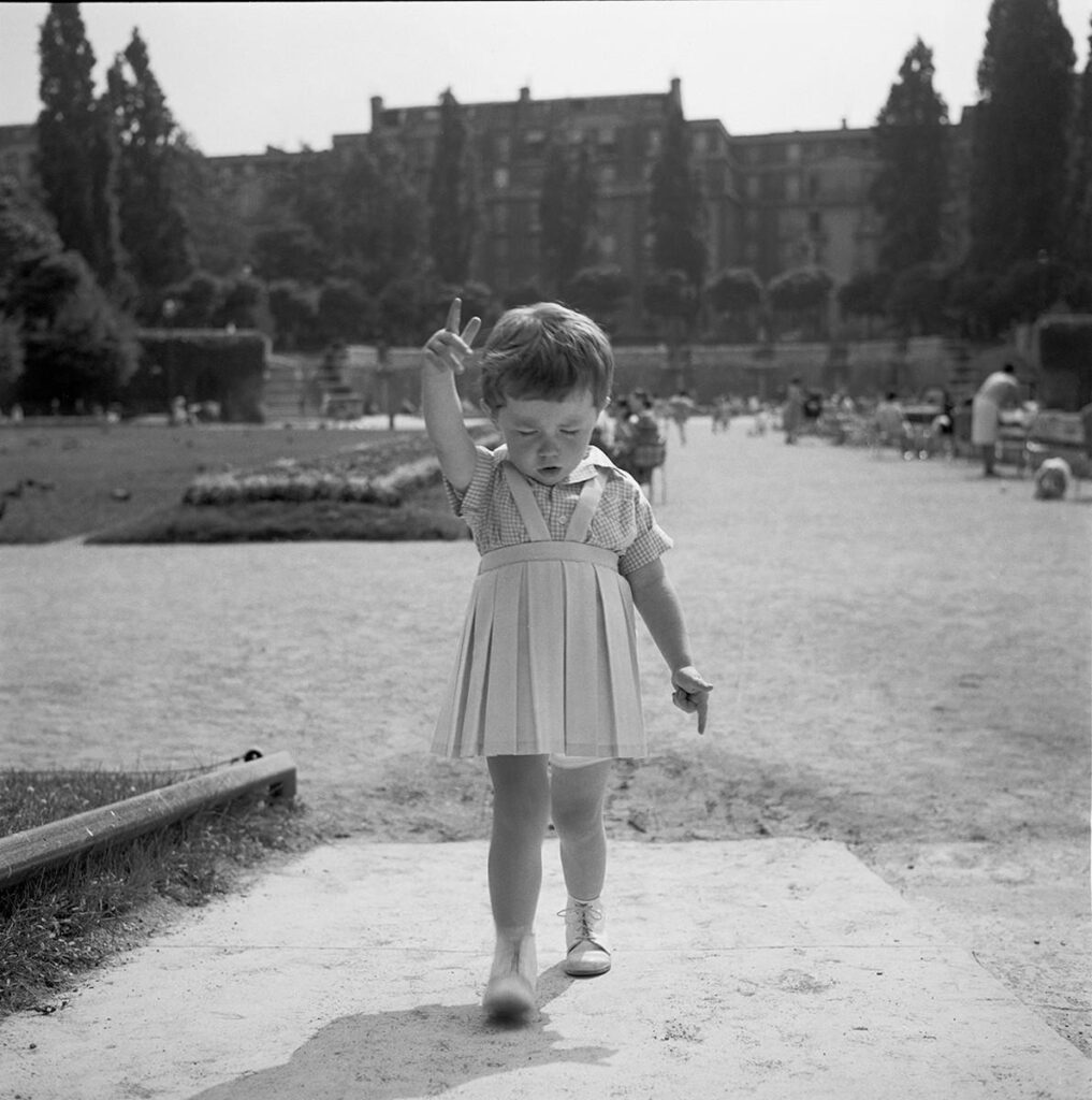une petite fille prédicatrice, le doigt levé dans un jardin parisien