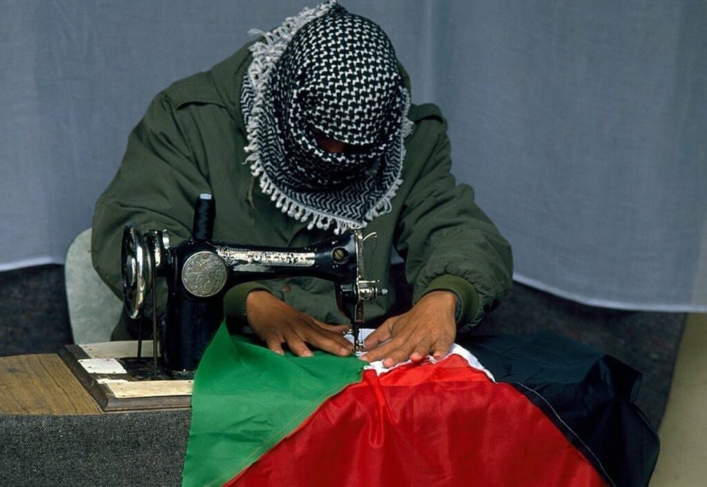 A Palestinian demonstrator sews a Palestinian Liberation Organization flag