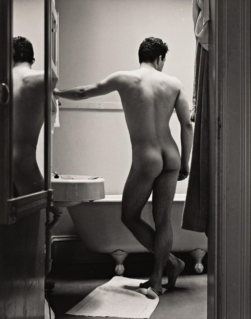 un homme nu, de dos, la main appuyée sur le mur, regarde la baignoire