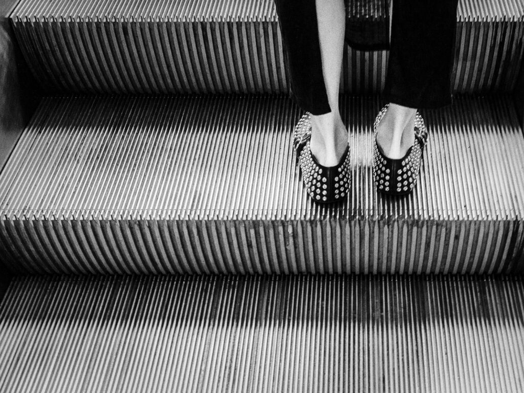 les pieds d'une femme élégante ayant choisi de souliers assortis aux marches de l'escalator emprunté