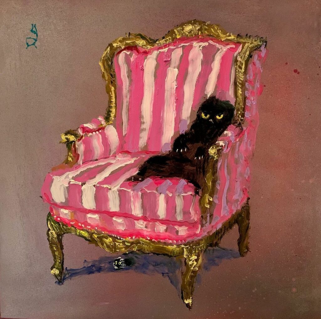assis dans un fauteuil rose, un chat noir semble méditer des projets diaboliques