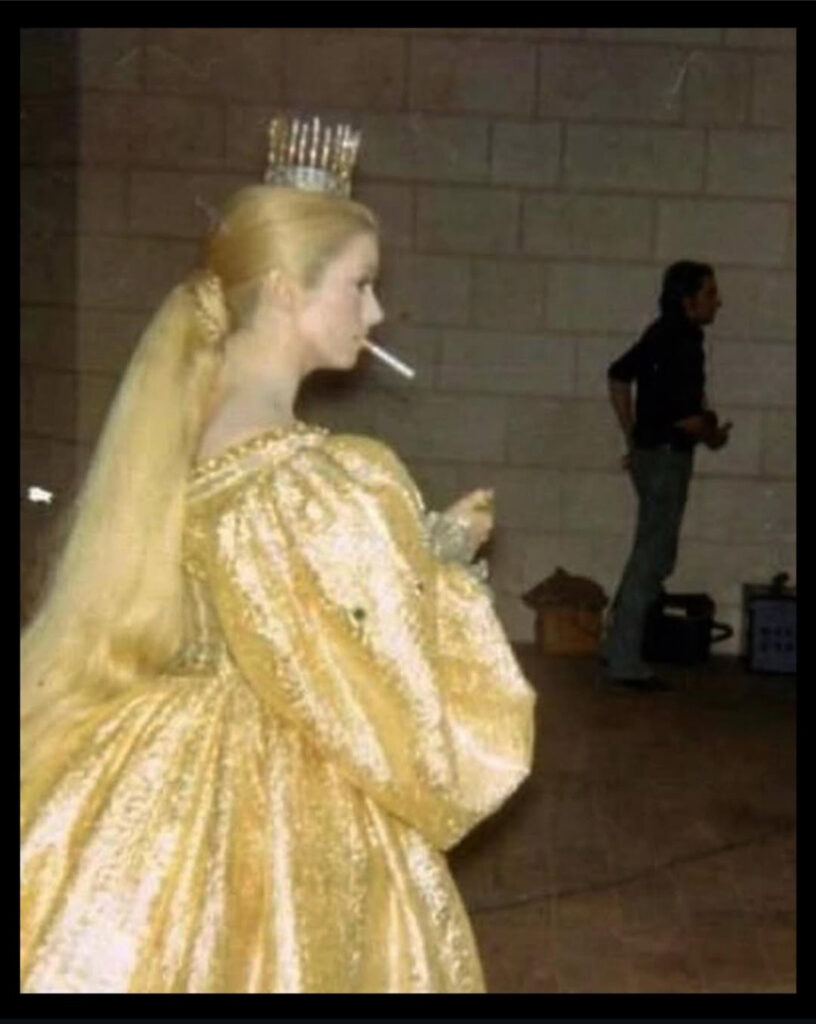Catherine Deneuve sur le tournage de Peau d’âne portant  sa robe couleur du soleil et fumant sa première cigarette de la journée