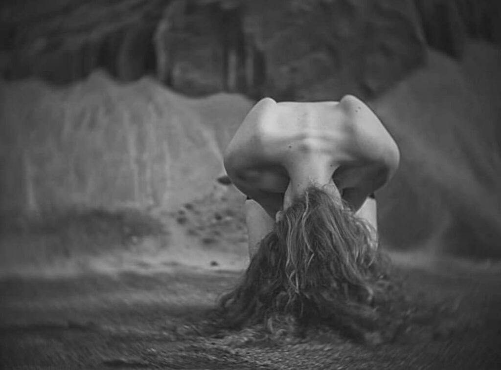 une femme nue prosternée, ses cheveux comme des racines la reliant à la terre