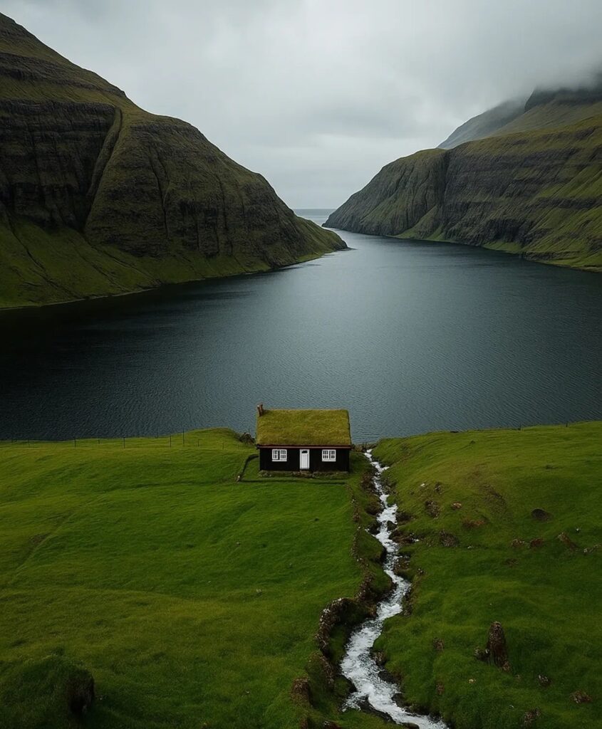 au bord d'un fjord, une petite maison à la toiture végétalisée aux Îles Féroé 