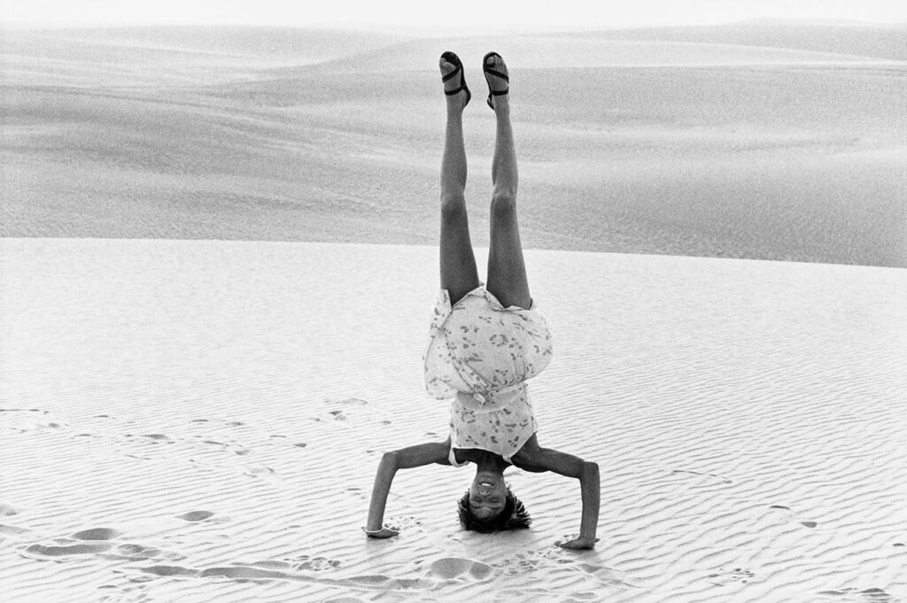 une femme faisant le poirier sur le sable des dunes