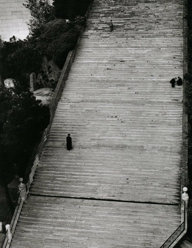 un ecclésiastique gravit les marches d'un escalier monumental semblant dépourvu de fin