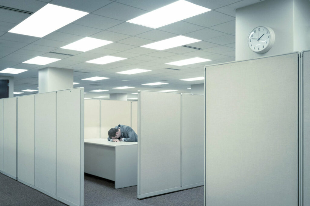 un homme dans un espace de travail désert, le front appuyé sur son bureau