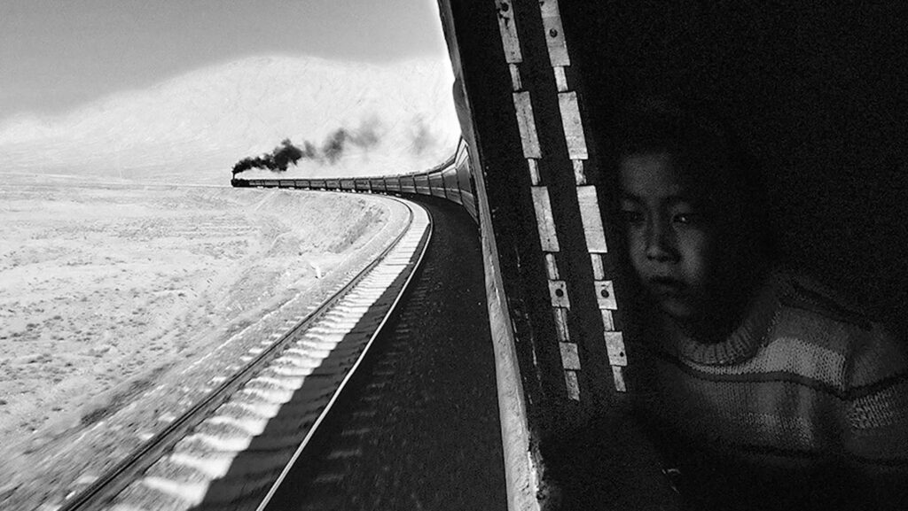 un train à vapeur dans une courbe immense, un jeune garçon à l'une des fenêtres