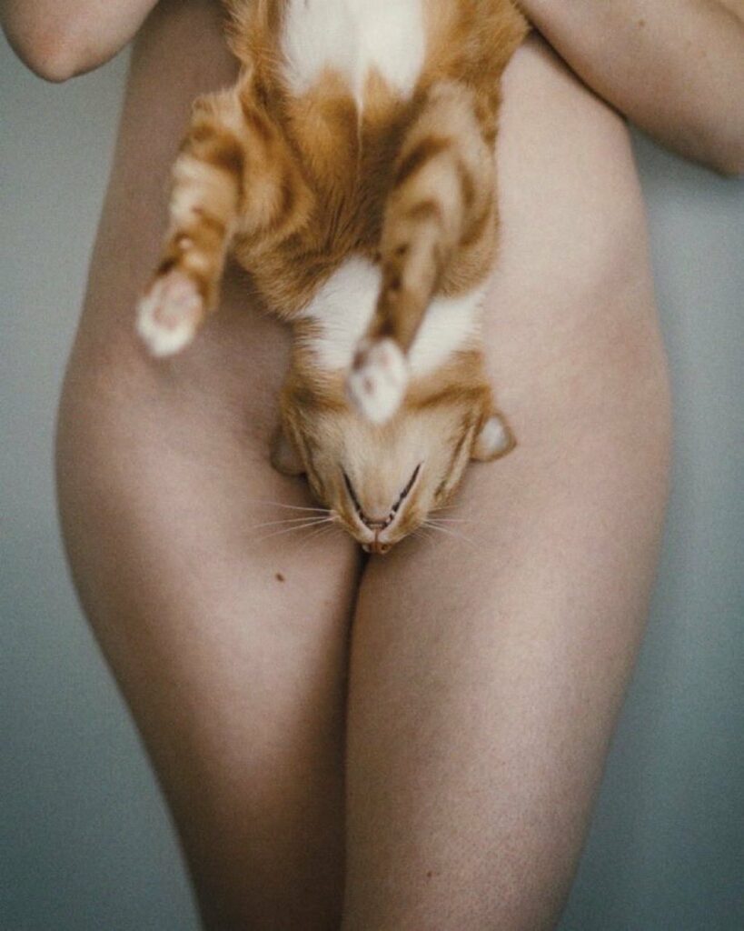 une femme nue tient sa chatte à l'envers, la bouche de celle-ci devant son sexe