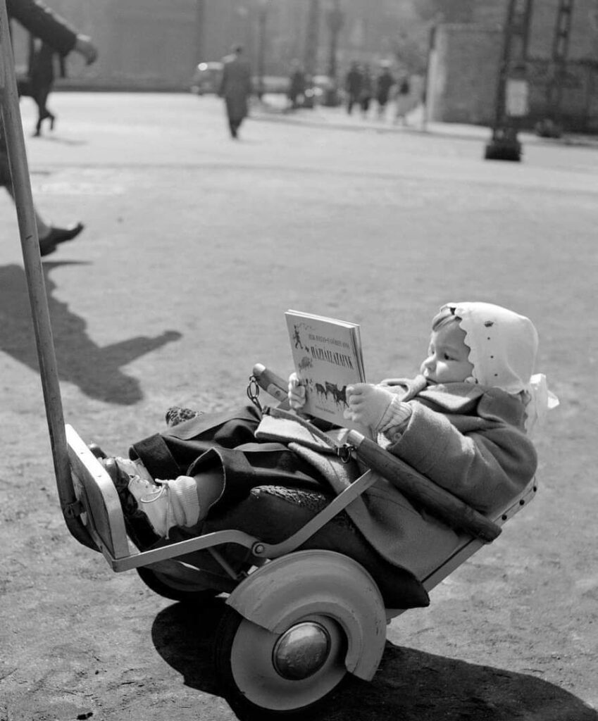 dans la rue, chaudement emmitouflé et bien installé dans son fauteuil-remorque-poussette, un enfant découvre un ouvrage pour la jeunesse