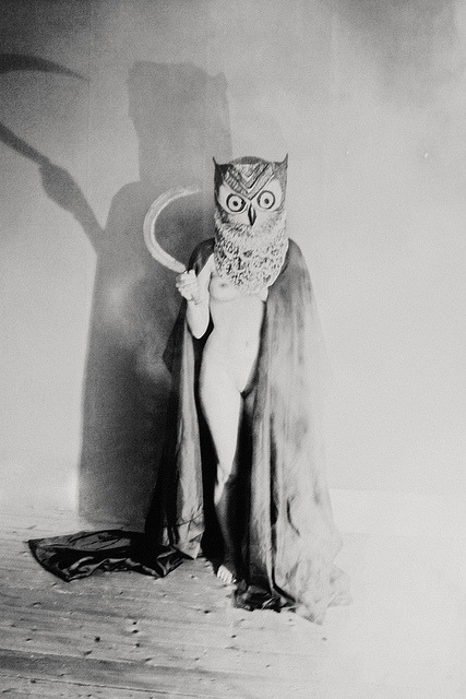 une femme nue à tête de hibou portant une toge et brandissant une faucille