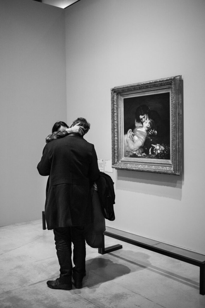 un couple s'embrasse au musée devant un tableau intitulé "le baiser"