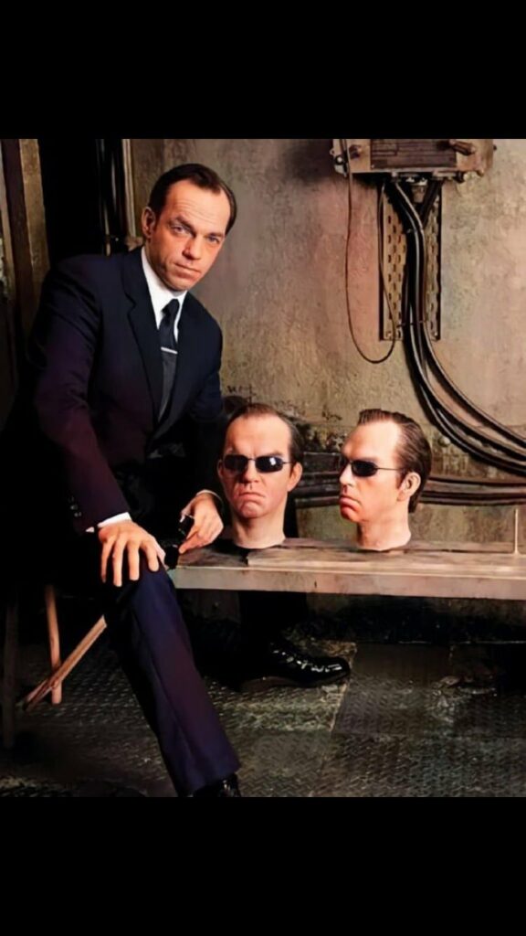 le héros de The Matrix posant à côté  de têtes de rechange