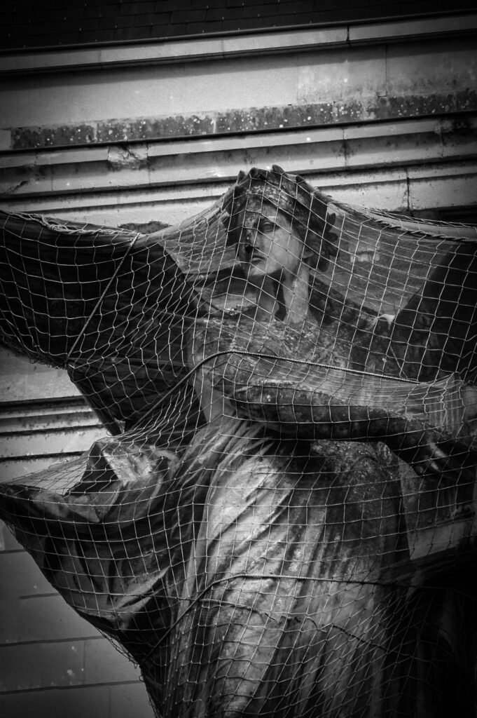 une statue de femme ailée prise dans un filet