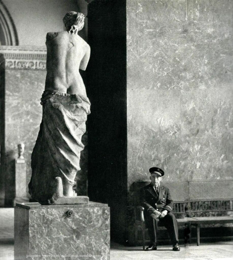un gardien de musée monte la garde à côté d'une statue de femme à demi dénudée