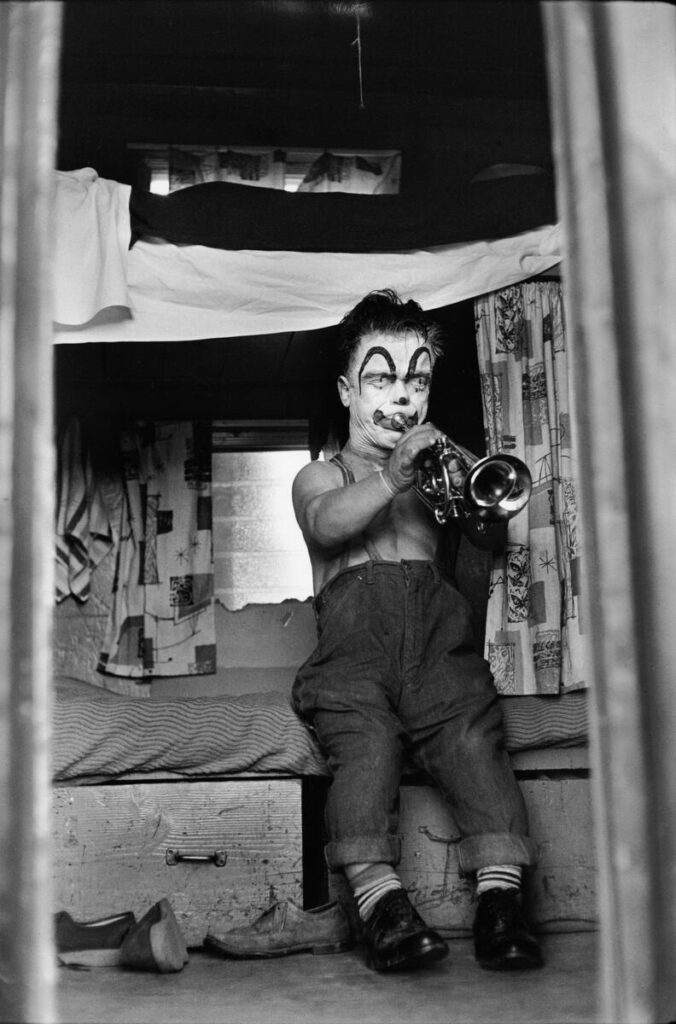 un clown nain jouant de la trompette assis sur sa couchette