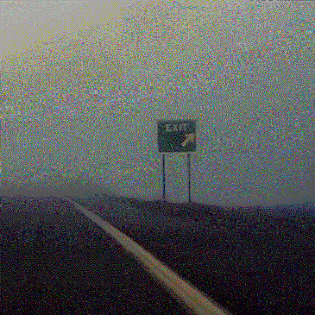 un panneau indique la sortie sur une route noyée dans le brouillard