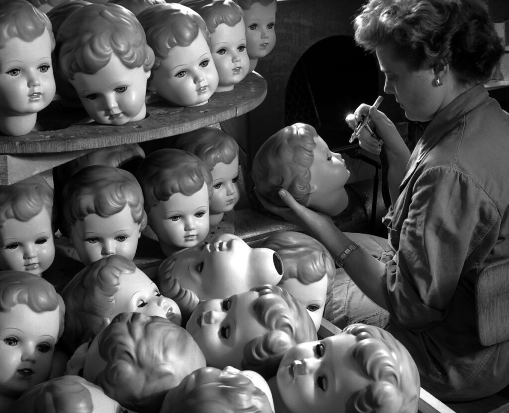 dans une usine de fabrication de jouets, une ouvrière met de la joie dans les yeux des poupées