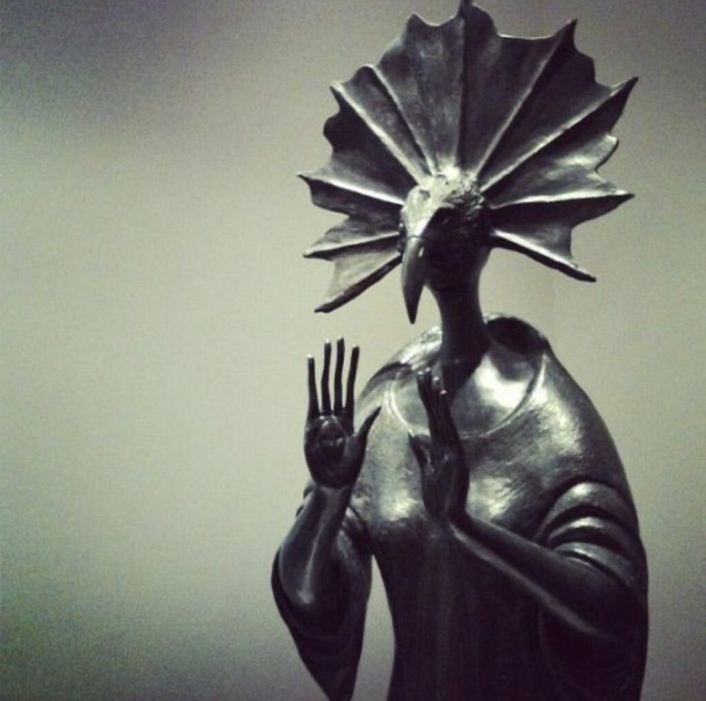 une déesse à tête d'oiseau appelle au calme en mettant ses paumes en avant