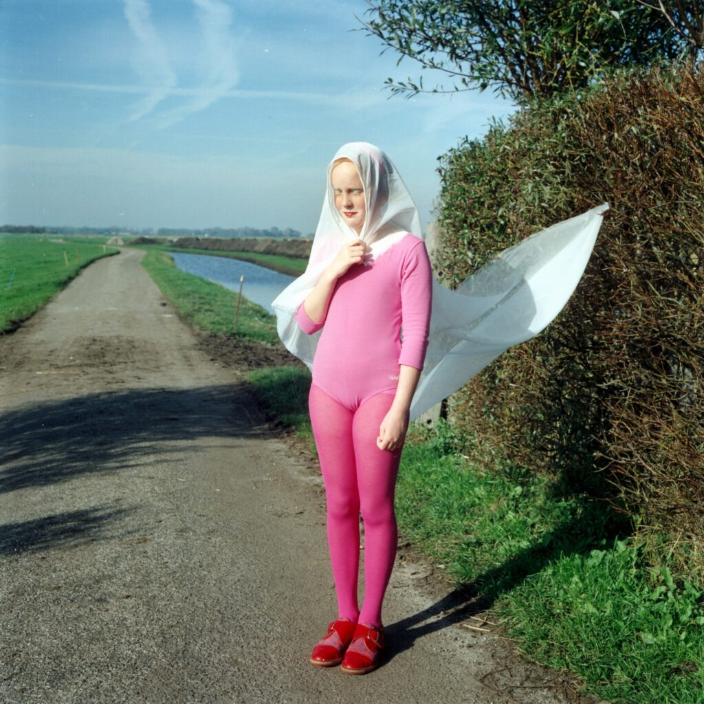 une jeune fille en rose sur une route de campagne déserte