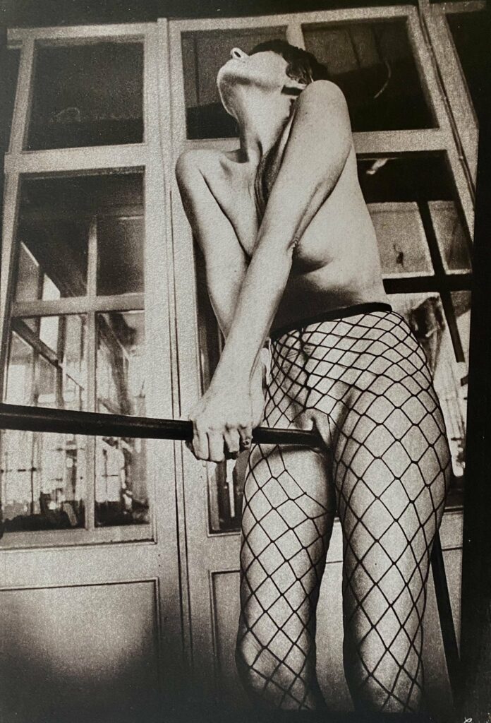 une danseuse en bas résille, à cheval sur la barre qui écarte les lèvres de sa vulve