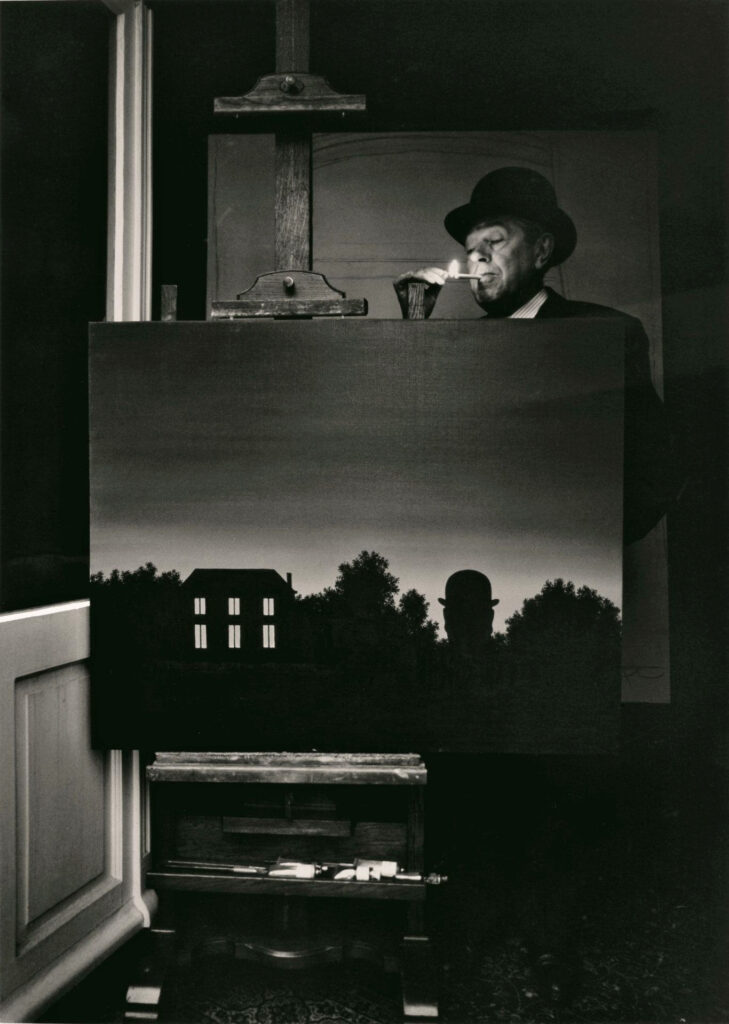 René Magritte à son domicile, photographié allumant une cigarette derrière son tableau La Fin Du Monde, 1963