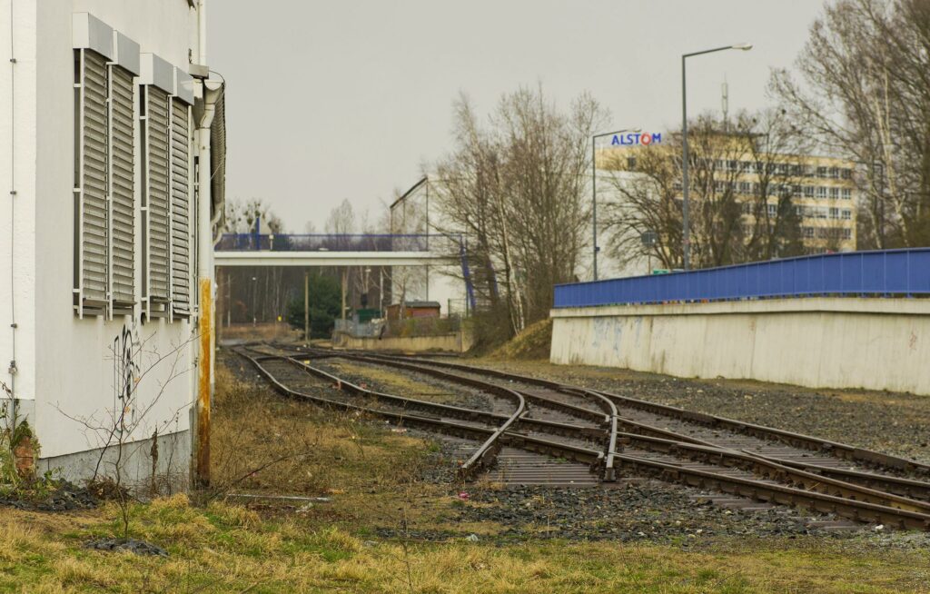 des rails s'achèvent dans l'herbe dans une zone industrielle 