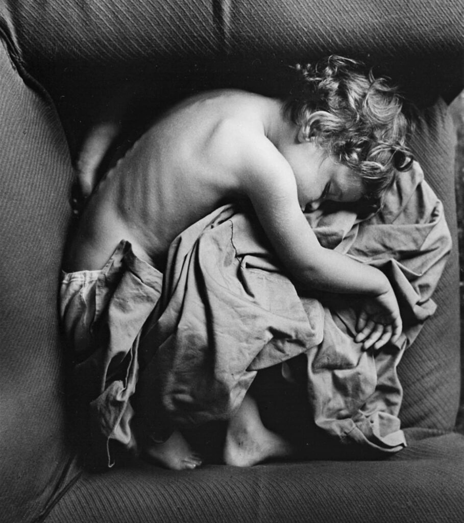 un enfant endormi en position foetale sur un fauteuil