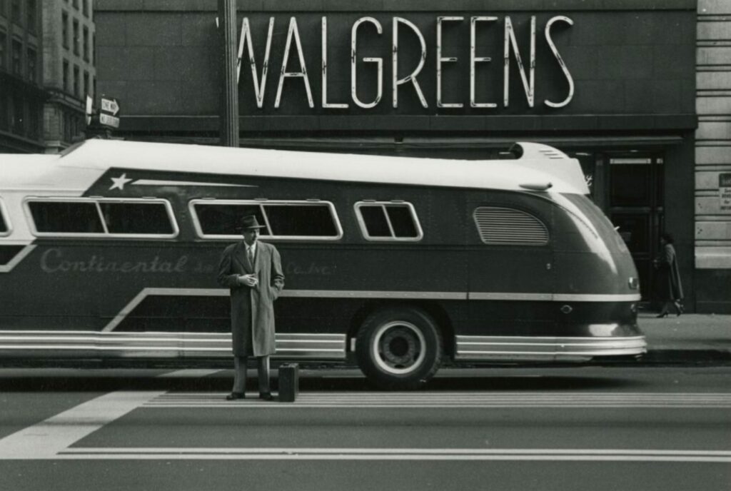 un homme debout à côté d'un bus à la ligne futuriste
