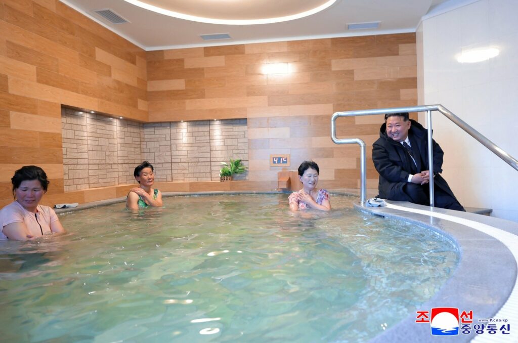 trois femmes coréennes du nord gênées par la visite surprise d'un Kim Jong Un rayonnant en manteau d'hiver pendant leur séance de soins non mixtes dans leur station thermale récemment rénovée