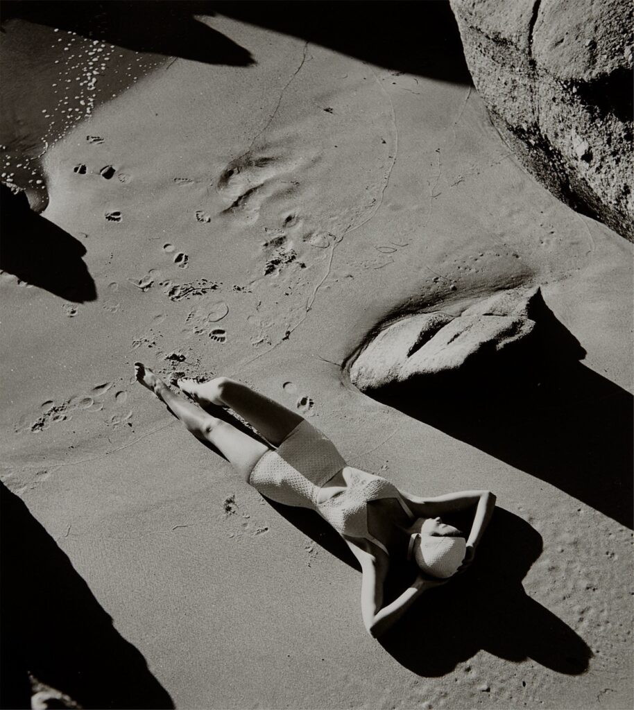 allongée dans une crique à l'abris des regards, une femme prend le soleil vêtue de son élégant maillot de bain en caoutchouc