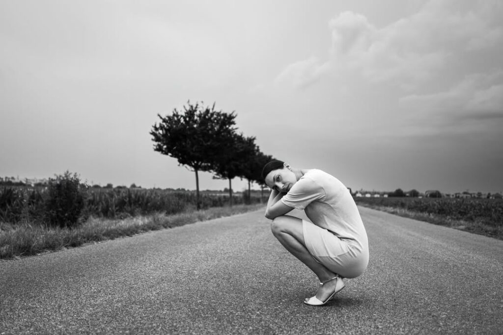 les arbres dressées comme des cheveux sur la tête d'une femme accroupie sur une route