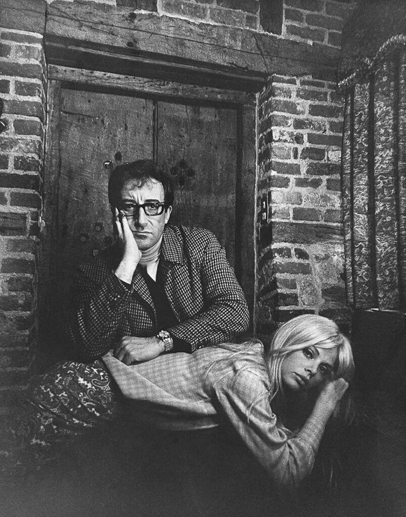 un homme, écrasé par la responsabilité qui pèse sur lui à l'approche du 8 mars, appuie sa tête sur sa main, ses coudes reposant sur une femme couchée sur ses genoux