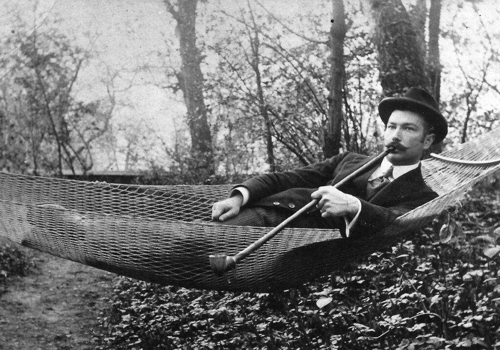 un fumeur de pipe suspendu entre deux arbres en forêt