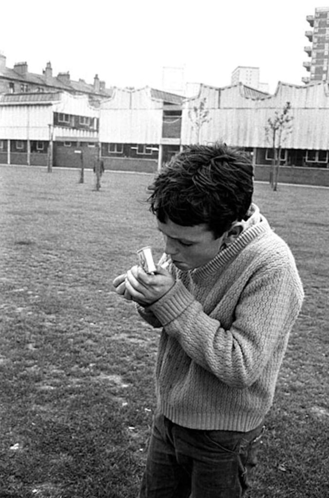 Un adolescent allume une cigarette lors du déblaiement des bidonvilles, dans le quartier de Gorbals à Glasgow, en Écosse, en 1968.