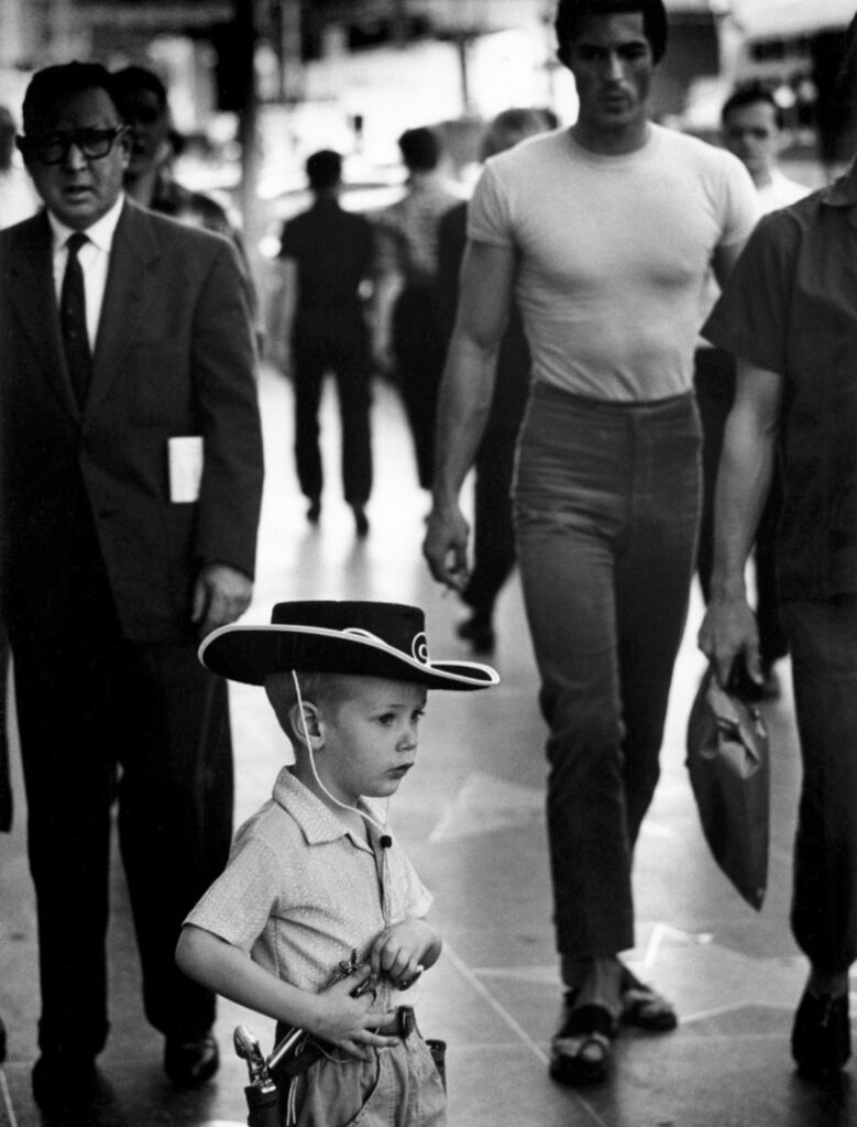 un petit garçon en costume de Zorro dégainant dans la rue son revolver de justicier