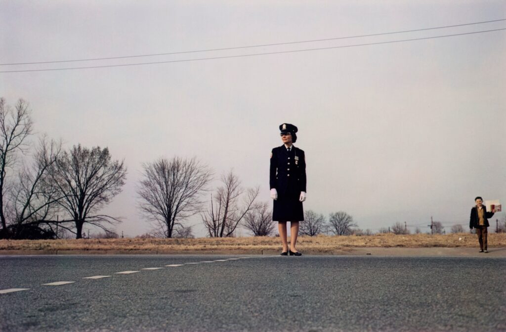 un agent de traversée des passages piétons en poste à l'approche d'un enfant unique sur une route déserte